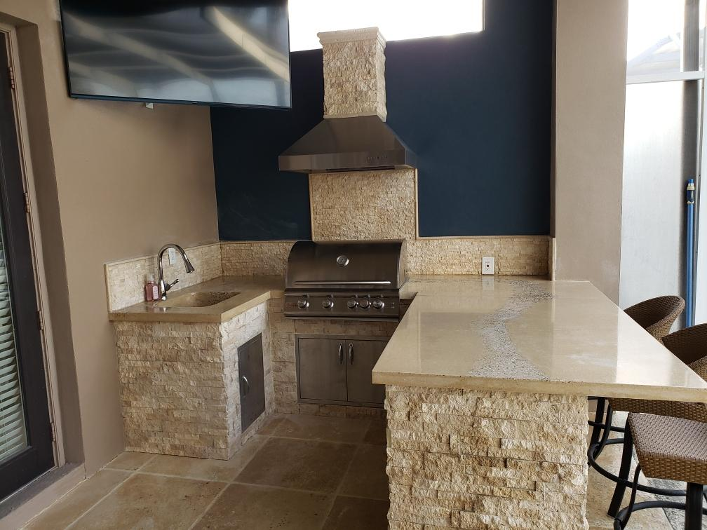 Bomb Shelter outdoor kitchen with stone veneer, grill, hood, sink and concrete countertop